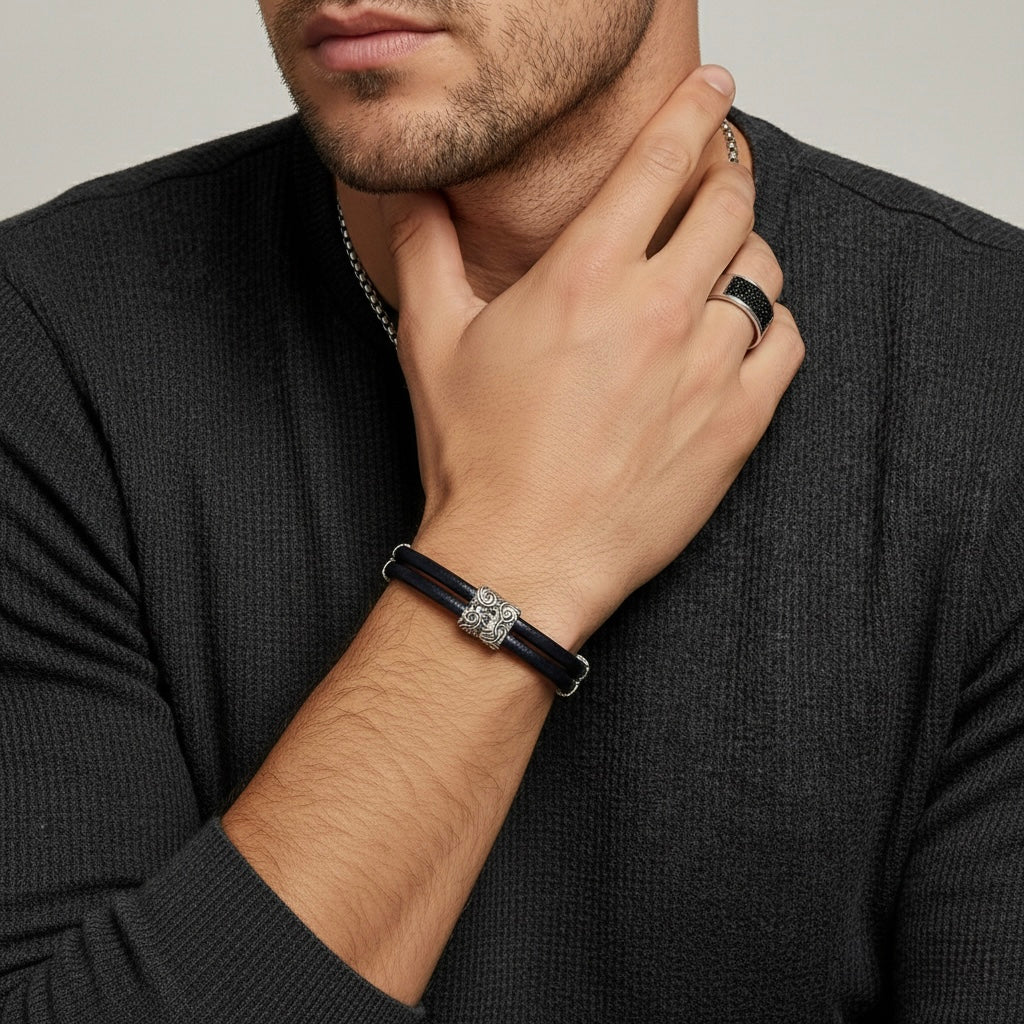 Man wearing a black leather bracelet with a silver clasp on his wrist.
