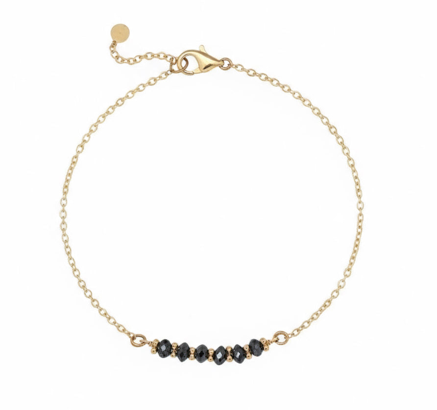 Gold bracelet with black diamond beads on a white background