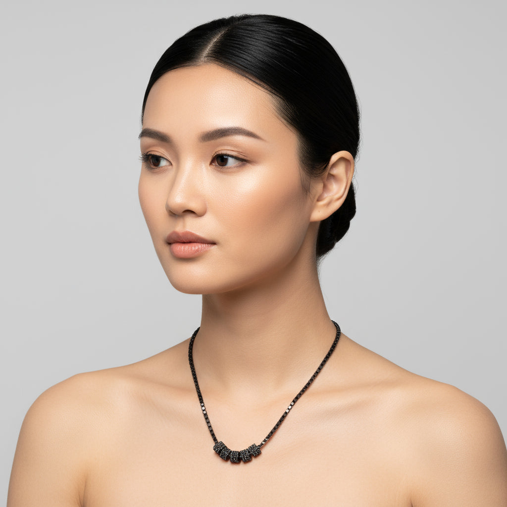 Woman wearing a black diamond cylinders necklace against a gray background