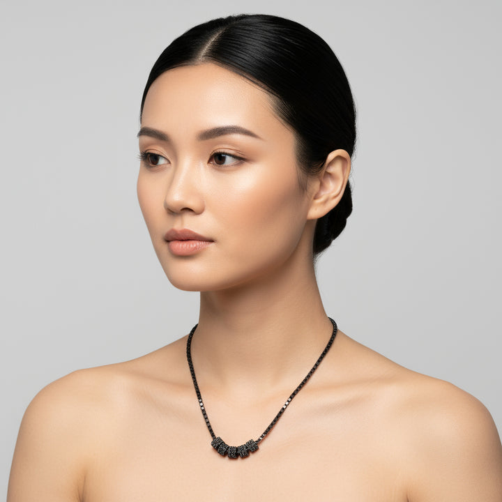 Woman wearing a black diamond cylinders necklace against a gray background